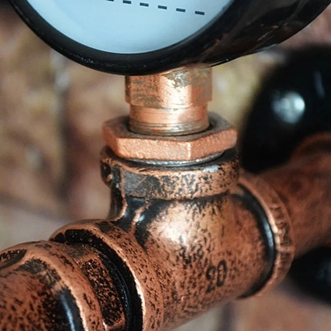 Pipe fitting components of steampunk wall sconce showing distressed copper finish, threaded pipe joints and locking metal nuts, close-up detail of construction