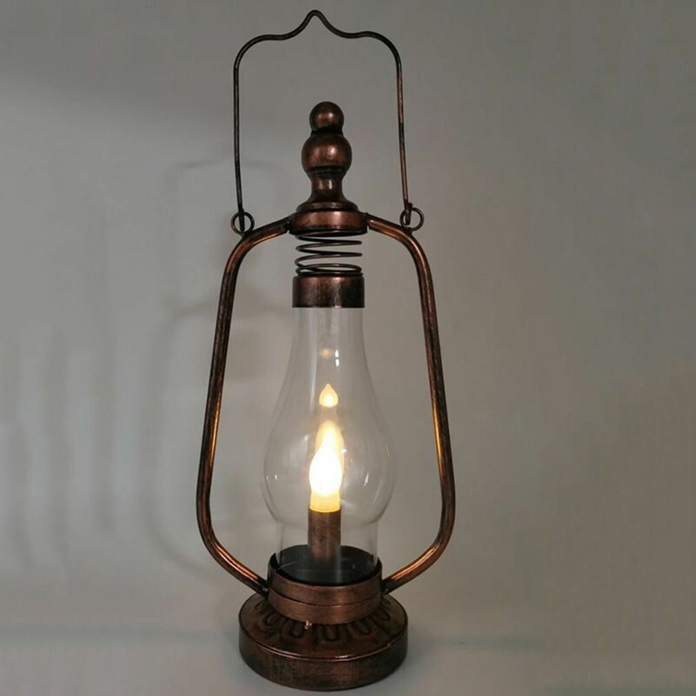 Steampunk portable lamp with distressed bronze metal frame and LED candle bulb, front low-angle view on grey studio background