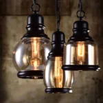 Amber steampunk pendant light with matte black metal fixture and teardrop-shaped glass shade, vintage Edison bulb illuminated