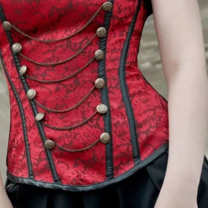 Close-up detail of red jacquard steampunk corset bodice showing antique brass buttons and chain accent