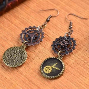 Asymmetrical steampunk drop earrings flat lay on bamboo surface, featuring textured disc and mechanical gear pendant design