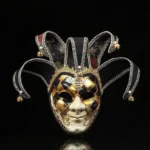 Black and gold Venetian jester steampunk masquerade mask with checkered eye design, bell-adorned jester caps, and cracked facial texture - frontal studio view