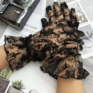 Black gothic lace steampunk gloves with rose and cross baroque motifs, sheer mesh construction, displayed overhead on vintage desk with antique camera and Victorian decor