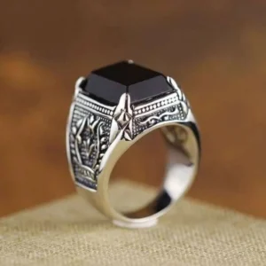 Black onyx steampunk ring front three-quarter view showing square gemstone with engraved vintage patterns and polished silver band on linen background