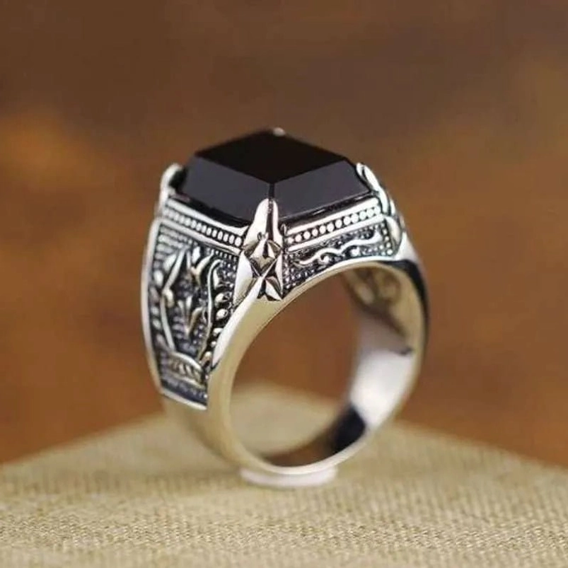 Black onyx steampunk ring front three-quarter view showing square gemstone with engraved vintage patterns and polished silver band on linen background