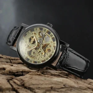 Black steampunk skeleton mechanical watch with gold hollow movement and Roman numeral dial, displayed on dark wooden surface with oblique top-down view showcasing leather strap detail