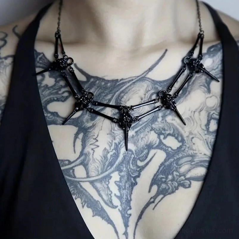 Black steampunk bird skull necklace with articulated metal skeleton design, worn by tattooed model for gothic alternative fashion styling