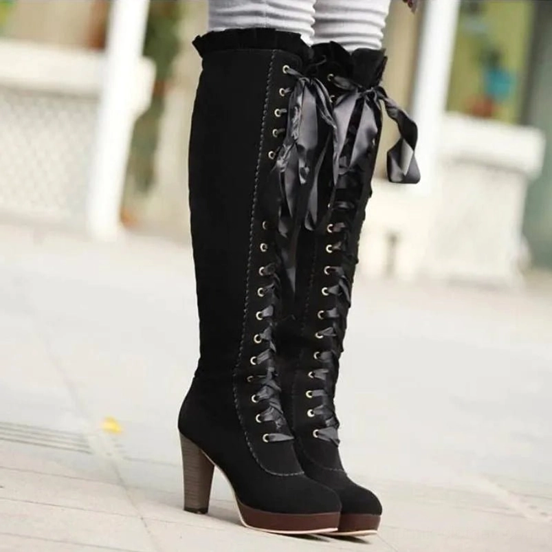 Black steampunk over-the-knee boots with platform block heel, front lace-up design, and ruffled top edge, worn with striped leggings on outdoor sidewalk