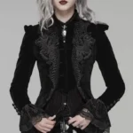 Black velvet gothic steampunk jacket with ornate grey embroidery on front bodice, lace-trimmed cuffs, detailed close-up showing hand-placed embellishment patterns and rich fabric texture