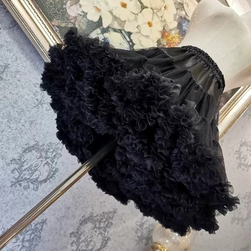 Black fluffy voluminous petticoat tulle steampunk skirt low oblique view highlighting extra-full multi-layered ruffled texture and silhouette
