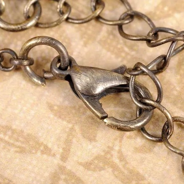 Antiqued brass cable chain with reinforced lobster clasp for steampunk necklace, showing chain link detail and secure fastening mechanism