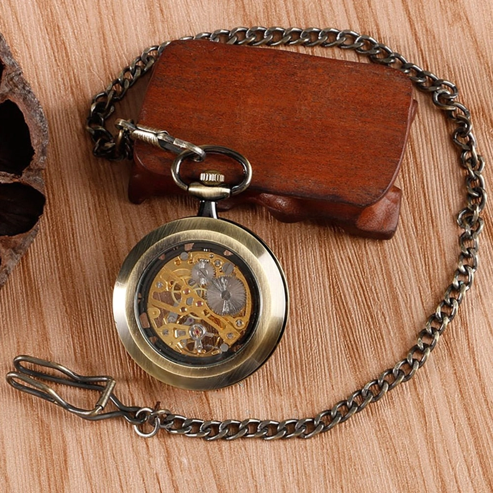 Mini bronze skeleton pocket watch side profile showing compact body and linked pocket chain on vintage wooden display