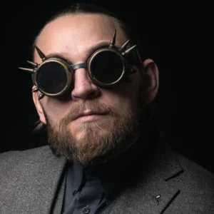 Bronze steampunk welding goggles with metal spikes and dark tinted lenses, frontal view worn by male model