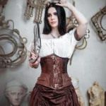 Brown jacquard steampunk underbust corset with copper hook closures front view on model, vintage studio setting