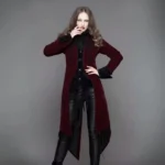 Burgundy gothic velvet tailcoat steampunk coat worn by model - three-quarter front view showing ornate black scroll embroidery and asymmetrical split hem design
