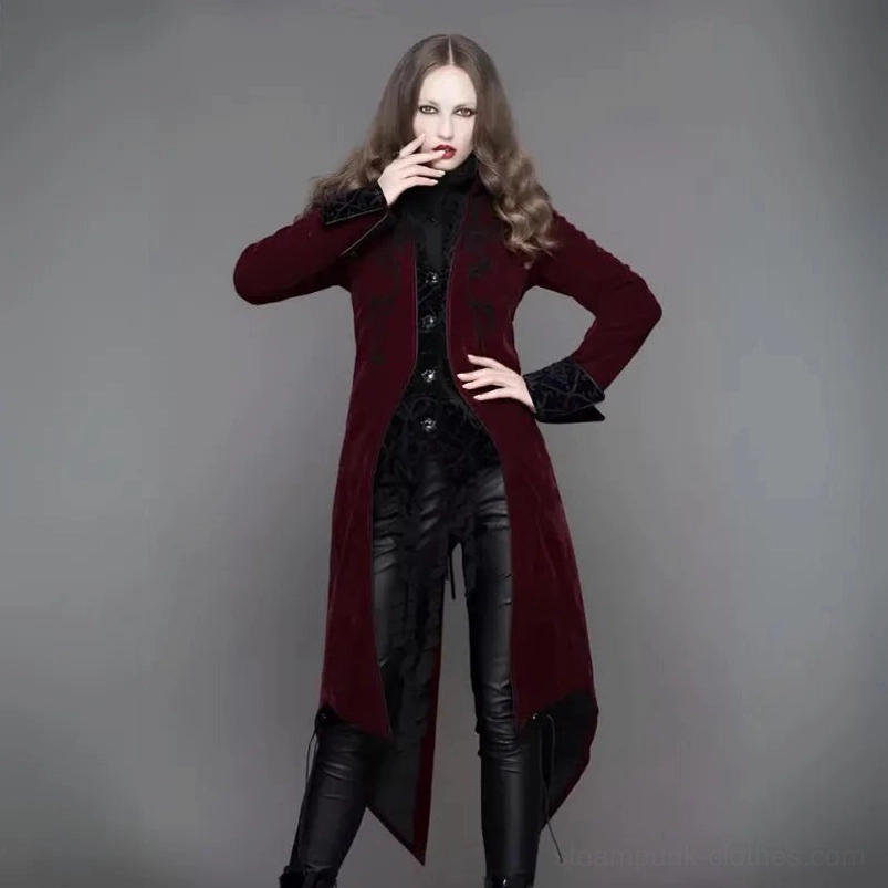 Burgundy gothic velvet tailcoat steampunk coat worn by model - three-quarter front view showing ornate black scroll embroidery and asymmetrical split hem design