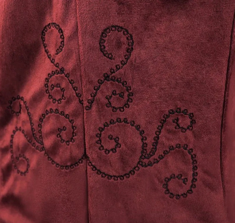 Ornate black scroll stitch embroidery detail on burgundy velvet - curved decorative stitching showing steampunk gothic craftsmanship and textile artistry