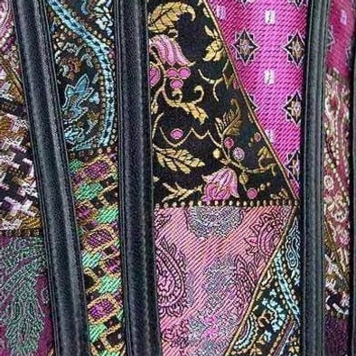 Steampunk corset side close-up detail showing black vertical boning and mixed floral paisley fabric pattern