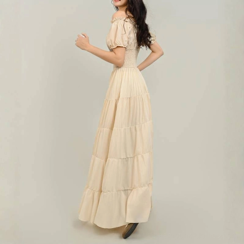 Cream tiered steampunk maxi dress back view showing floor-length skirt, smocked waist, and off-shoulder design with brown heeled shoes