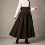 Dark brown high-waisted steampunk maxi skirt with pleated A-line silhouette and decorative buttons, full-body front view on fashion model