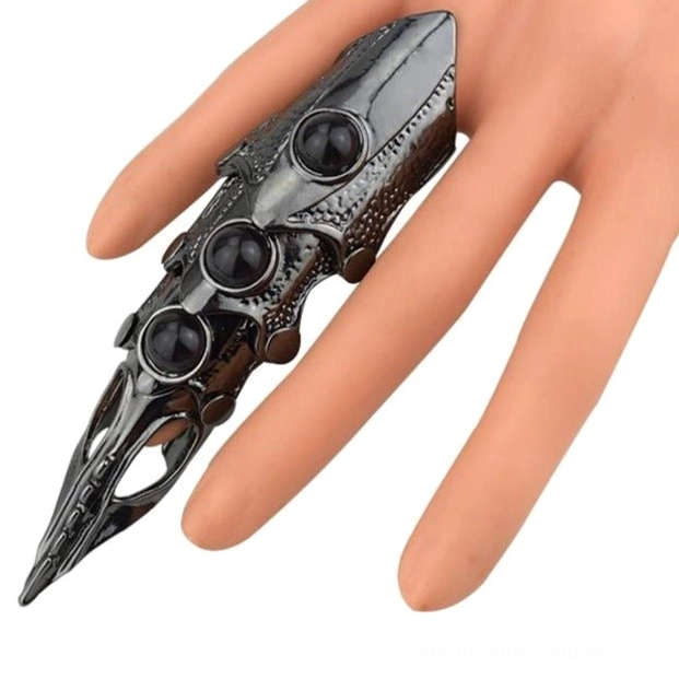 Finger armor ring fitted on mannequin hand demonstrating segmented joint design, gunblack metal construction, and three black resin gems in wearable position