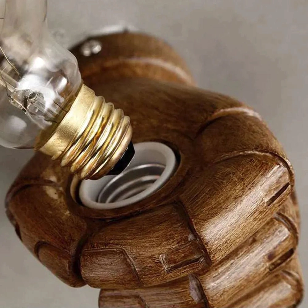 Fist-shaped lamp socket with resin wood-textured finish, exposed E27 bulb socket, and brass base in top-down close-up view