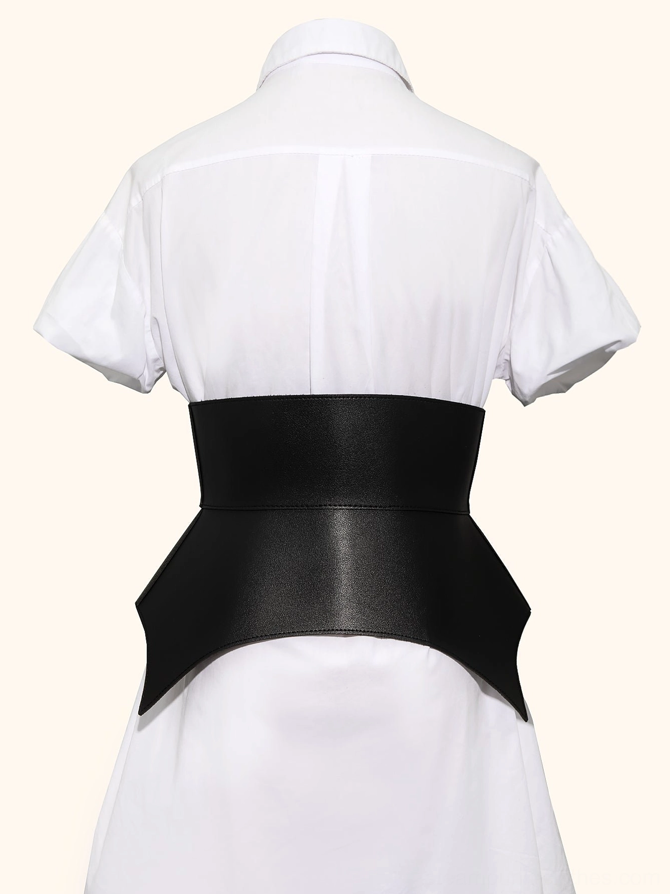 Steampunk bat corset belt rear view on mannequin wearing white shirt dress, showcasing asymmetric black faux leather hem and tapered back silhouette