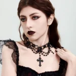 Black steampunk gothic cross choker necklace with layered beads and engraved pendant worn by female model in studio close-up