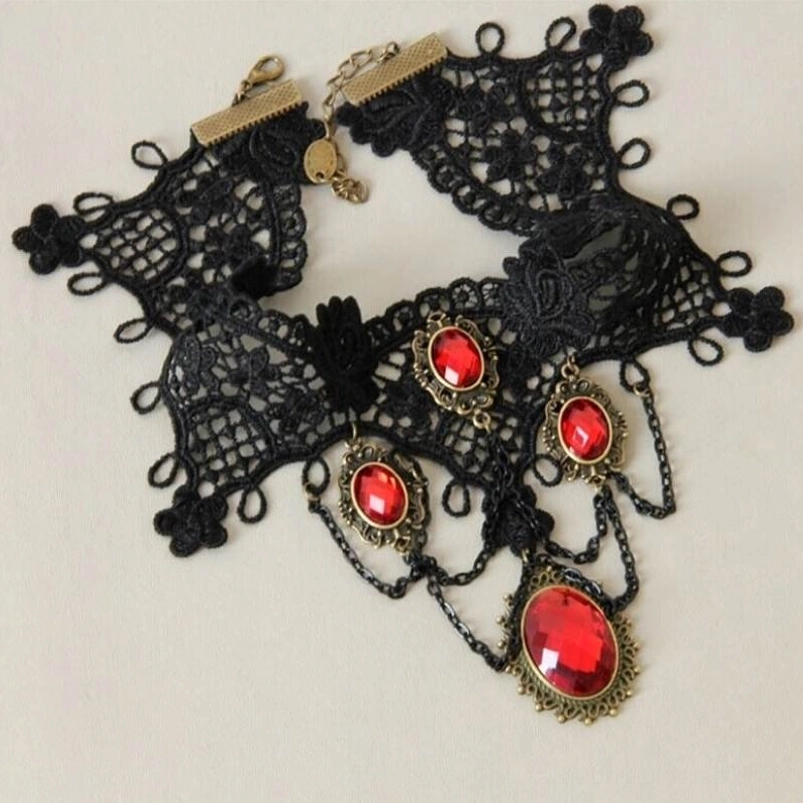 Handmade gothic vampire choker flat lay - displaying black crochet lace, multiple deep red gemstones, bronze-toned hardware and adjustable metal chains