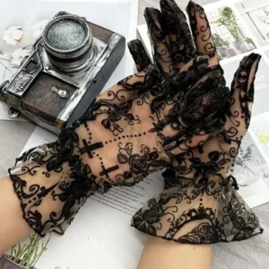 Sheer gothic lace gloves featuring baroque rose and cross prints, ruffled mesh cuffs, modeled on hands in three-quarter overhead view with retro camera and vintage cards