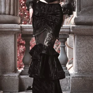 Steampunk gothic mermaid skirt side front angle showing fitted silhouette and beaded waist trim on stone courtyard backdrop