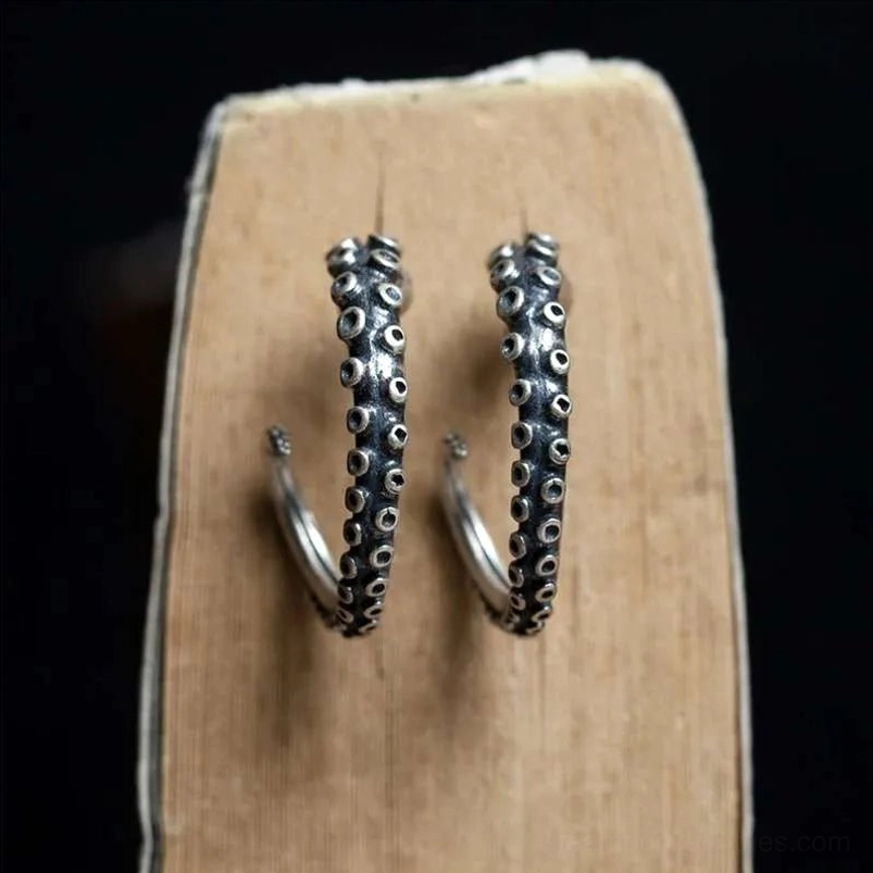 Front straight view of blackened silver tone octopus tentacle steampunk earrings with curved design and visible ear posts on dark background with wooden display block