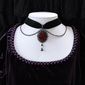 Gothic rose velvet choker necklace with red rose cameo pendant and black teardrop charm, displayed on neck mannequin against dark lace background, featuring layered gunmetal chains and filigree metalwork - front view steampunk jewelry