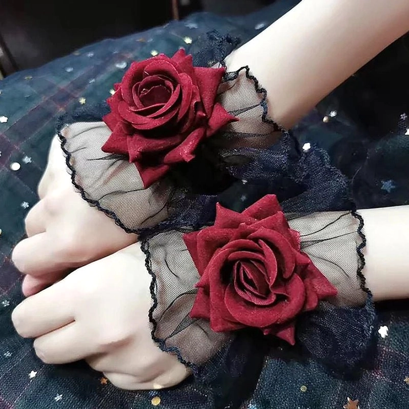 Victorian gothic rose wrist cuffs overhead view with wine-red velvet flocked roses and black sheer mesh ruffles on dark fabric with star embellishments