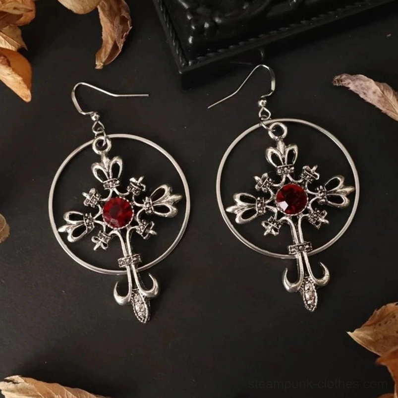 Complete gothic cross hoop earring set, symmetrically arranged showing both matching pieces with ornate fleur-de-lis crosses and red stone accents against dark moody background