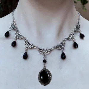 Victorian gothic choker necklace featuring carved silver floral chain design with black teardrop and oval gem pendants worn on neck, front close-up perspective