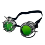 Green steampunk goggles with silver metal frame, green-tinted lenses, and spiked screw accents, featuring adjustable black elastic strap - left oblique view