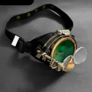 Green steampunk single goggle with brass-tone mechanical hardware, polarized green-tinted lens, black adjustable strap, and two attached magnifying lenses in studio flat lay view