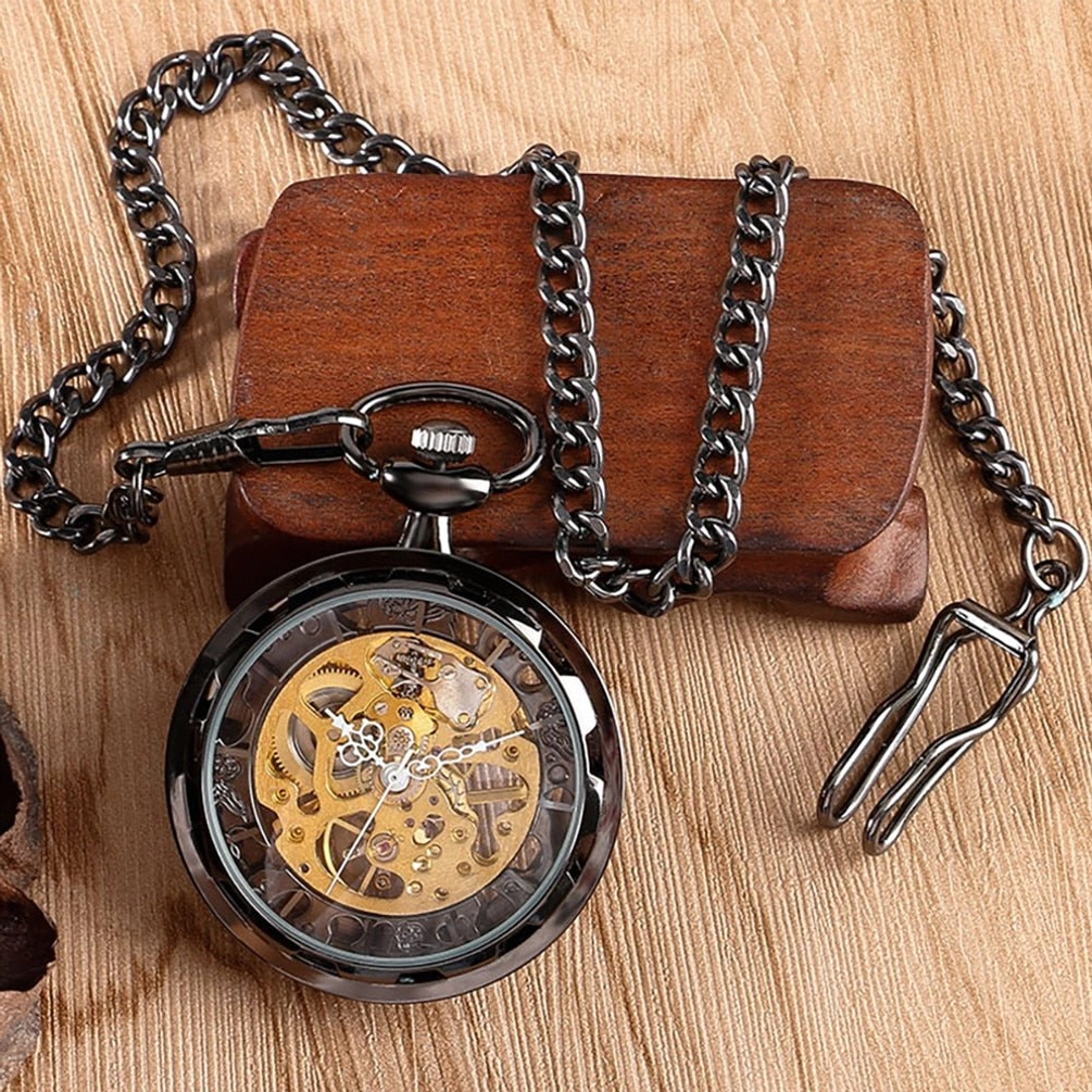 Gunmetal dark metal skeleton pocket watch with golden exposed gears and attached chain on wooden display stand