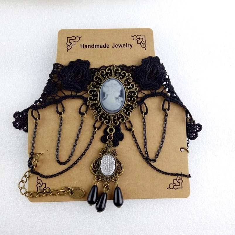 Handmade steampunk choker with black lace, cameo charm, and dangling chains displayed on handmade jewelry tag against white studio background