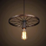 Industrial wagon wheel steampunk pendant lamp with bronze brushed metal finish and spoked wheel frame hanging in warm studio lighting