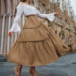 Khaki ruffled maxi skirt side rear view of model wearing in European architectural setting, showcasing flowy full-length skirt design with tiered ruffles and romantic silhouette