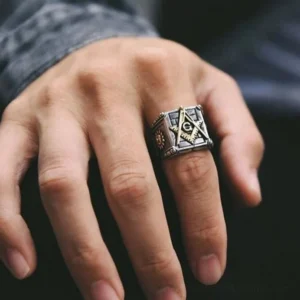Masonic steampunk ring with square compass and G emblem worn on male middle finger, showcasing aged silver finish against dark background