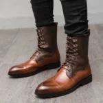 Men's steampunk lace-up combat boots front three-quarter view showcasing gradient two-tone brown split leather, reinforced metal lace eyelets, polished cap toe design, and durable non-slip rubber outsole