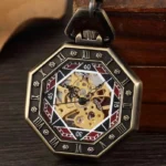 Octagonal steampunk skeleton pocket watch with bronze case, Roman numeral dial, and exposed brass mechanical gears displayed on wooden desktop with vintage foliage