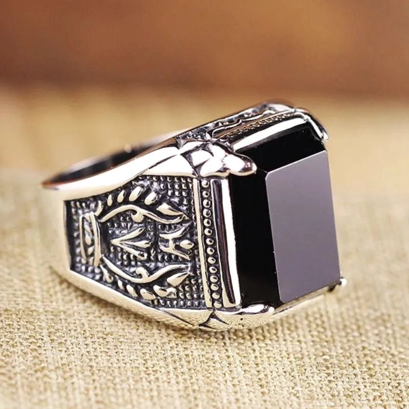 Vintage onyx signet ring left side profile view displaying square black stone with crown-style prong setting and royal engraved patterns in aged silver tone