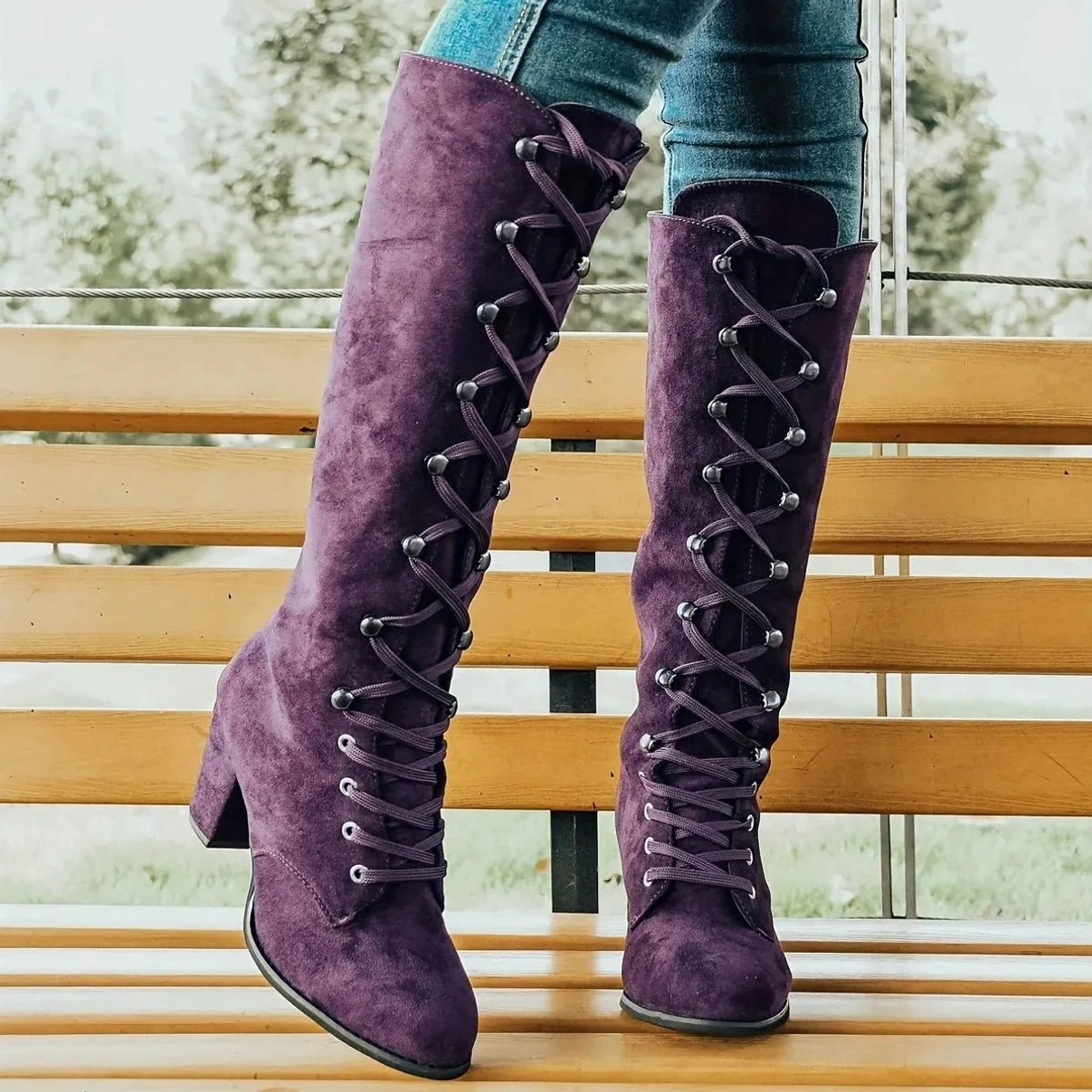 Purple knee-high lace-up steampunk boots worn with jeans, outdoor setting showing front lace design and rounded toe construction