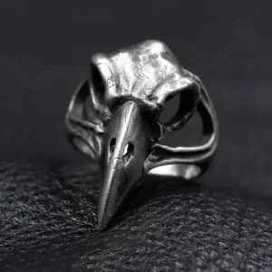 Raven skull steampunk ring front view, aged silver metal with hollow carved bird skull design and realistic beak details on dark leather background