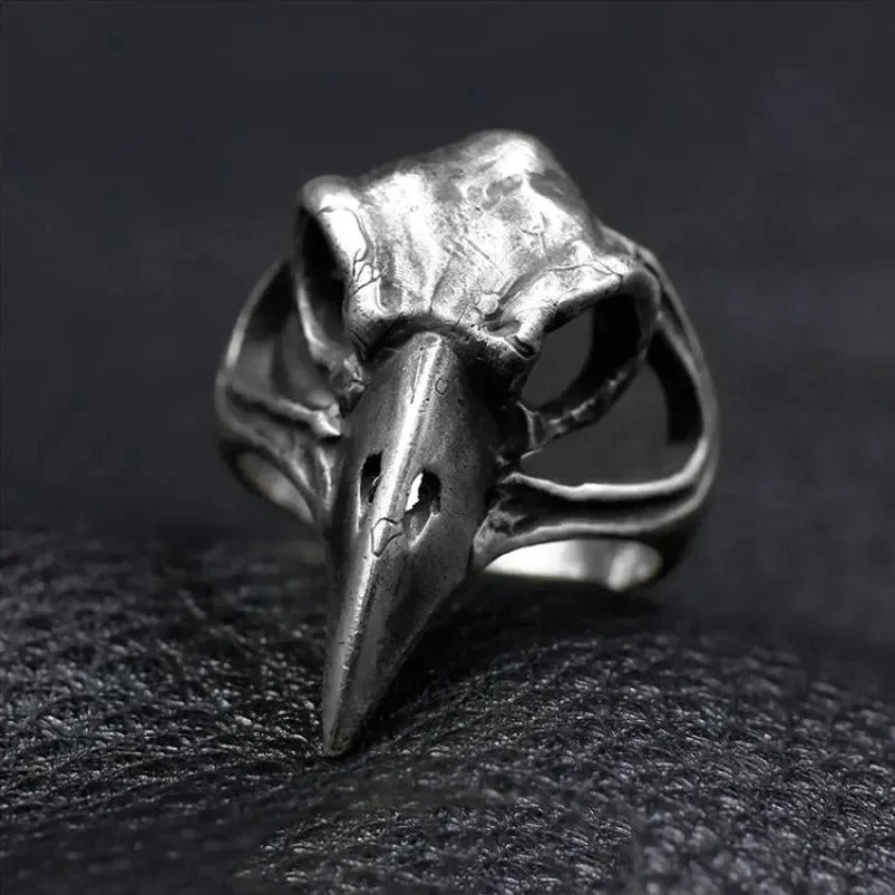 Raven skull steampunk ring front view, aged silver metal with hollow carved bird skull design and realistic beak details on dark leather background