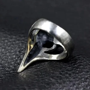 Raven skull steampunk ring side view, polished silver band with hollow carved raven skull and subtle gold accents inside the design